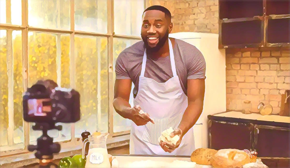 Young cooking african man speaker talking on digital camera recording vlog. African male vlogger or shooting blog filming reportage advertising video, coaching.